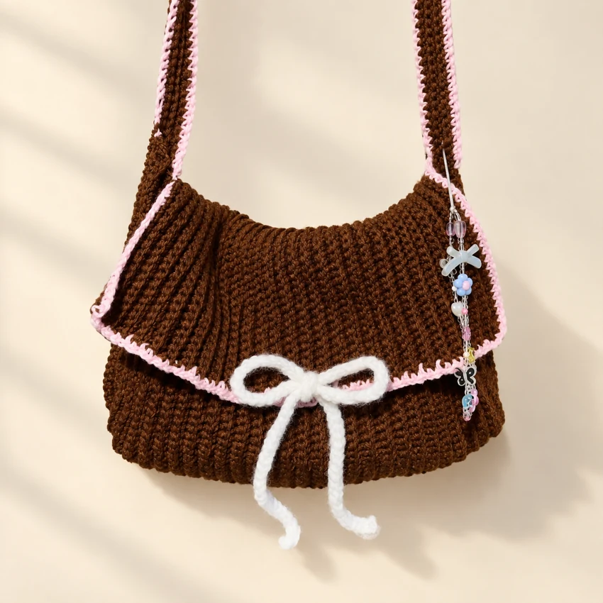 A chocolate brown crochet shoulder bag with a cream bow
