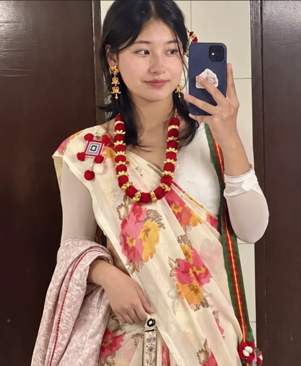 Aachal smiling in a cream floral sari with a red handmade necklace