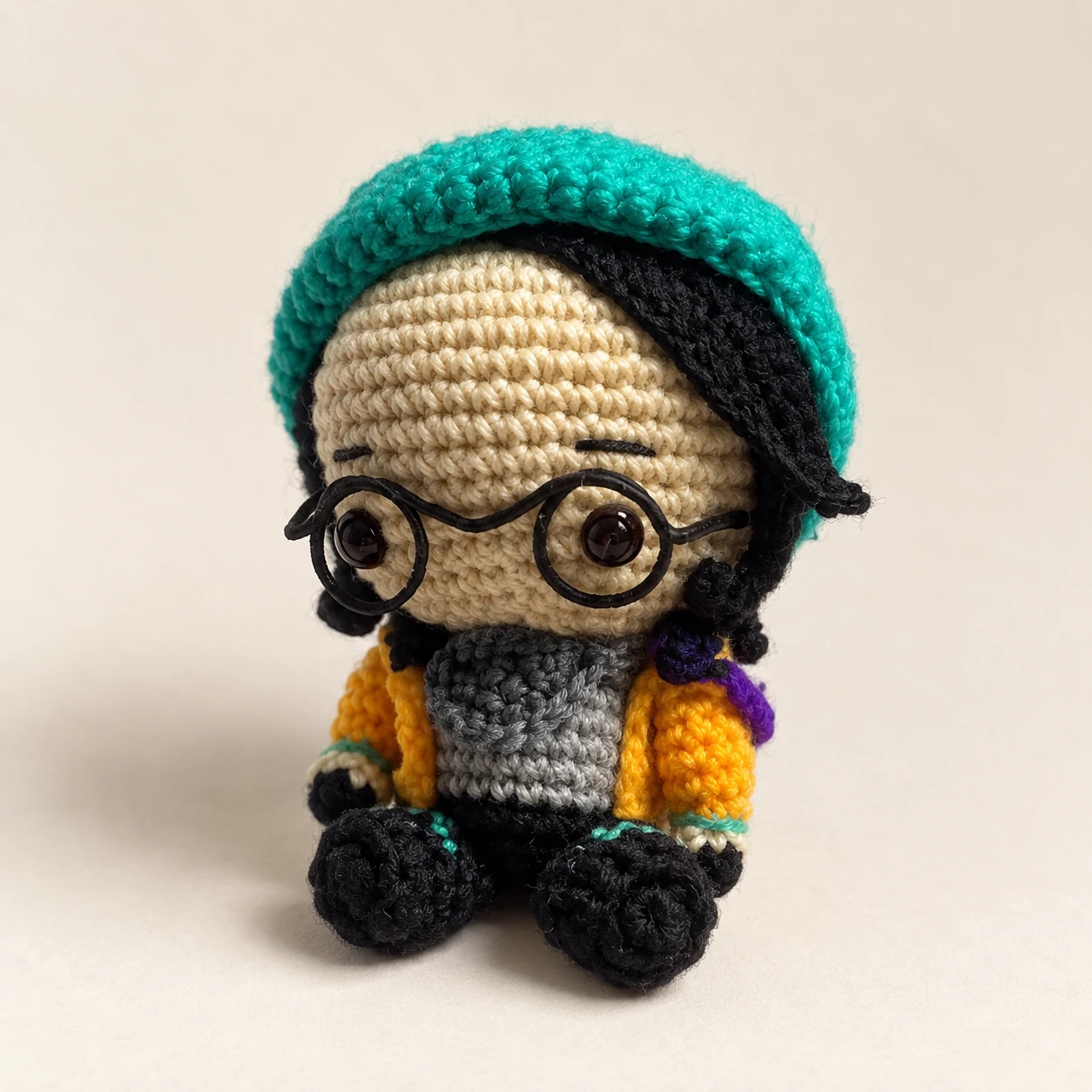 Killjoy crochet doll with round glasses, a green beanie and yellow jacket