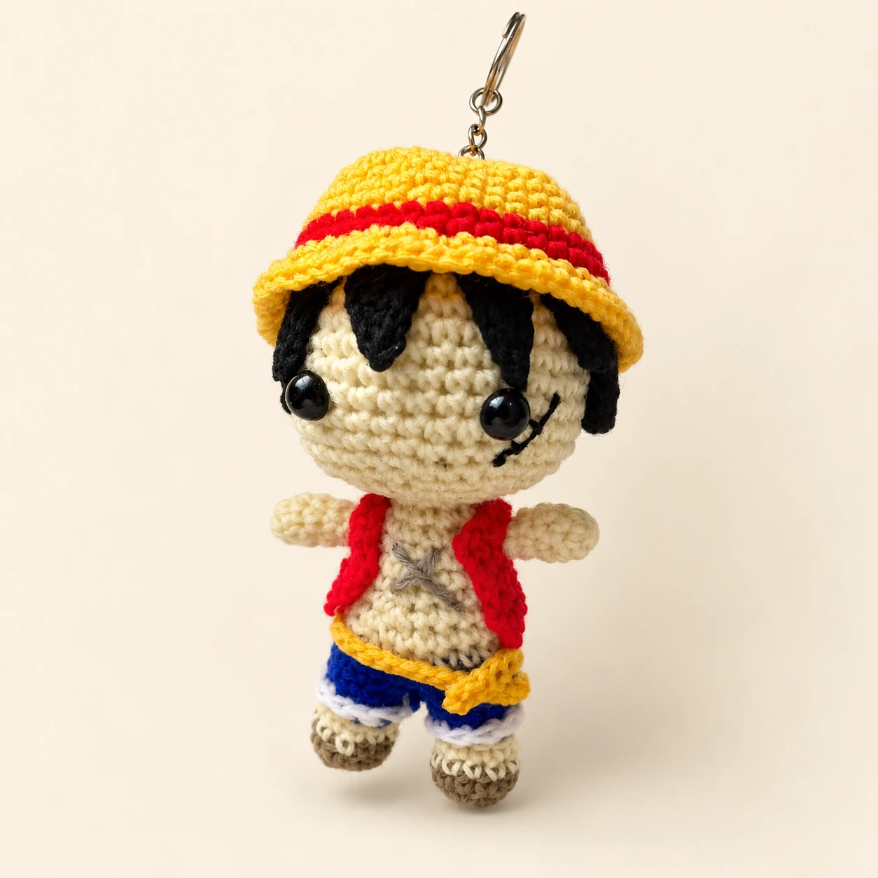 Luffy crochet keychain wearing a yellow straw hat, red vest and blue shorts